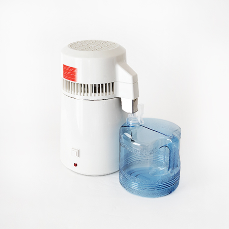 Photo of a product. This is Imber Puro water distiller. The appliance is depicted in the middle of the frame, next to it is a blue PVC jug. The water distiller is white.