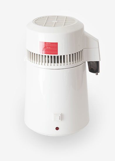 Photo of the Imber Puro water distiller. The distiller is shot frontally, over a white plain background. The dim shadow around the subject gives the impression of it floating mid air. The water distiller is white, it has a plastic body and a stainless steel nozzle. The image has a graphic quality, it conveys a sense of purity, simplicity and precision.
